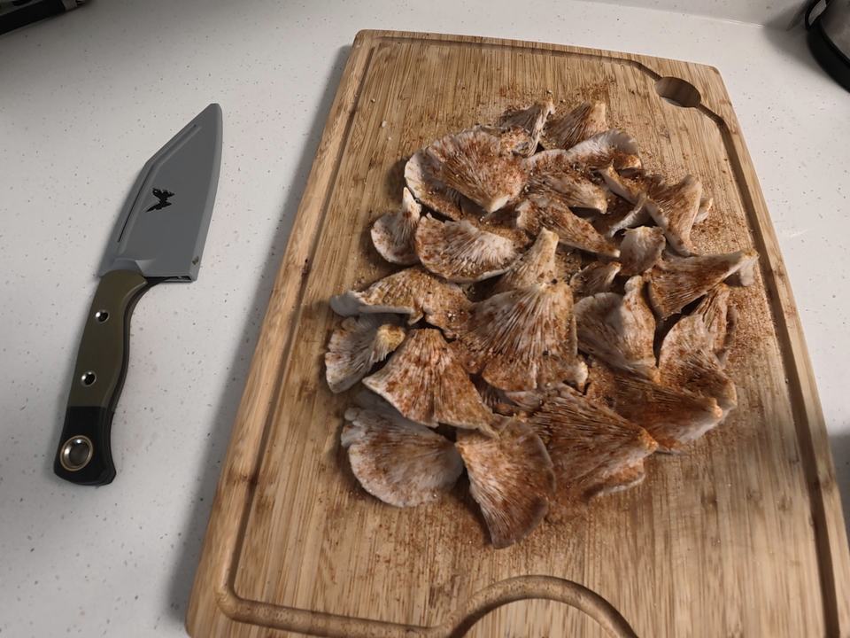 Oyster mushrooms sliced and seasoned on a cutting board