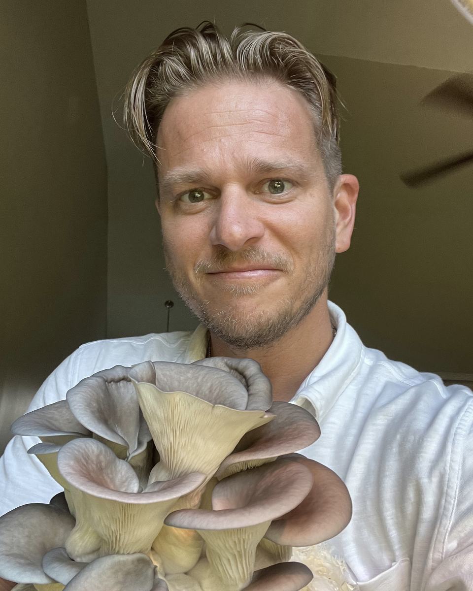 Don holding a cluster of oyster mushrooms he grew