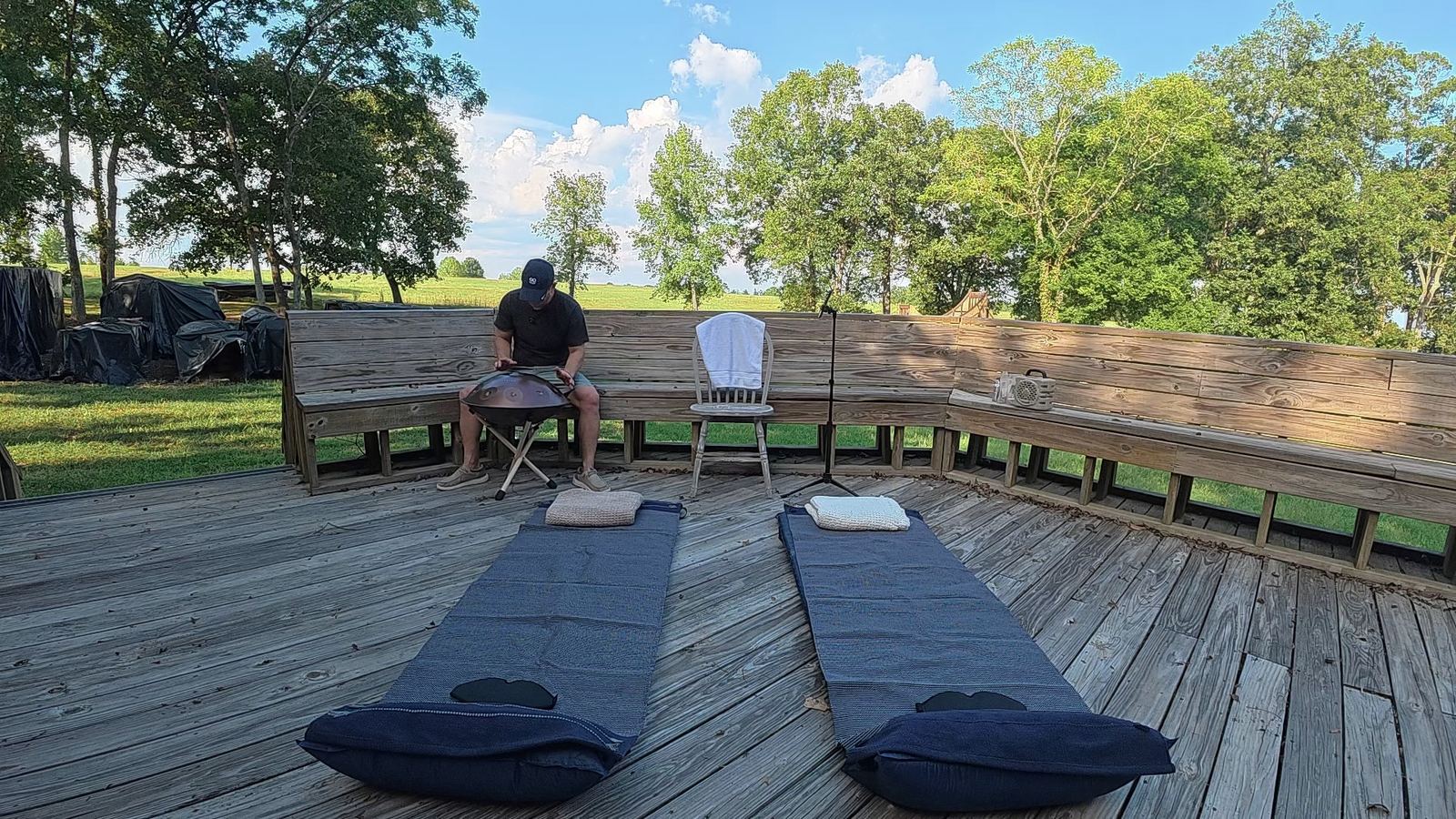 A handpan on a wooden deck with two mats laid out